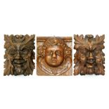 A matched pair of carved oak Green Man wall masks length 16cm, with a similar example of a cherub.