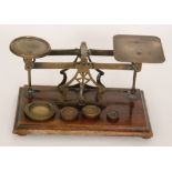 A set of Avery brass postal scales and four associated weights on a walnut base,