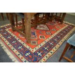 A 20th Century Kazak style rug the central orange panel with three styalised hooked lozenges and