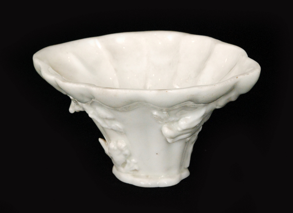 A Chinese Qing Dynasty 18th Century libation cup in the form of rhinoceros horn relief moulded with