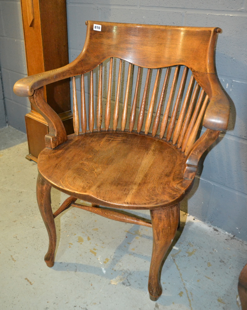 A pair of early 20th Century oak lath back elbow chairs with solid saddle shaped seats above