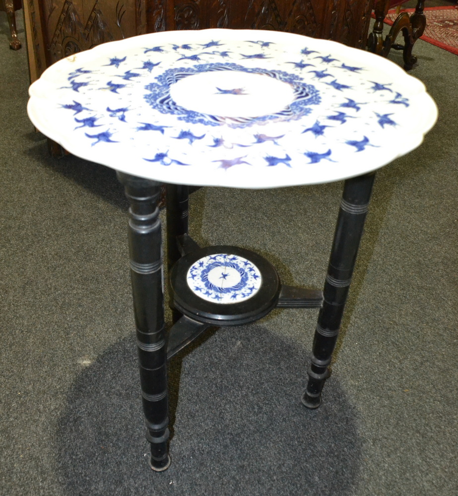 A late 19th Century occasional table with blue ceramic swivel top on ebonised legs,