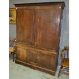 An early 19th Century oak linen cupboard enclosed by a pair of panel doors over a cupboard plinth