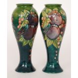 A pair of Moorcroft Pottery footed baluster vases decorated in the Finches pattern designed by