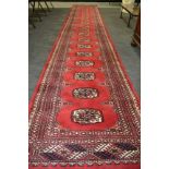 A 20th Century North West Persian runner with a central row of guls on a red ground,