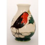 A Moorcroft Pottery vase decorated with a robin perched amidst holly branches,