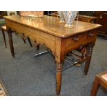 A Victorian oak side table with a single end drawer above a fret-cut apron, raised to turned legs,