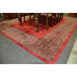 A 20th Century Indian wool carpet the central red ground within a stylised gul border 366cm x 274cm