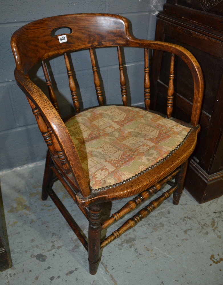 An early 20th Century spindle back elbow chair with a saddle shaped seat and stretcher frame,