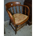 An early 20th Century spindle back elbow chair with a saddle shaped seat and stretcher frame,