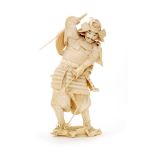 A Meiji period carved okimono ivory study of a standing Samurai in full battle armour holding a