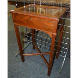 A small Edwardian walnut bijouterie cabinet with lift glazed top on square legs united by a cross