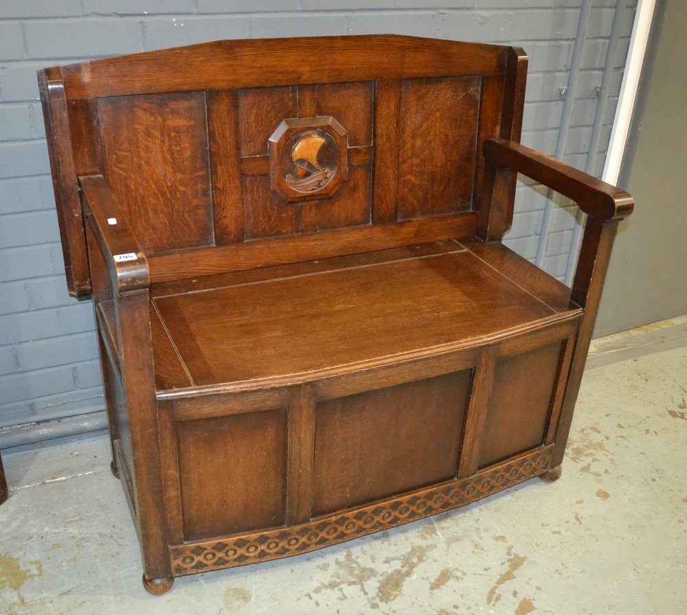 A mid 20th Century oak veneered monk's bench, raised to bun feet, width 107cm.