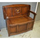 A mid 20th Century oak veneered monk's bench, raised to bun feet, width 107cm.