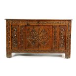 An 18th Century and later carved oak coffer with lozenge panelled front on stiles,