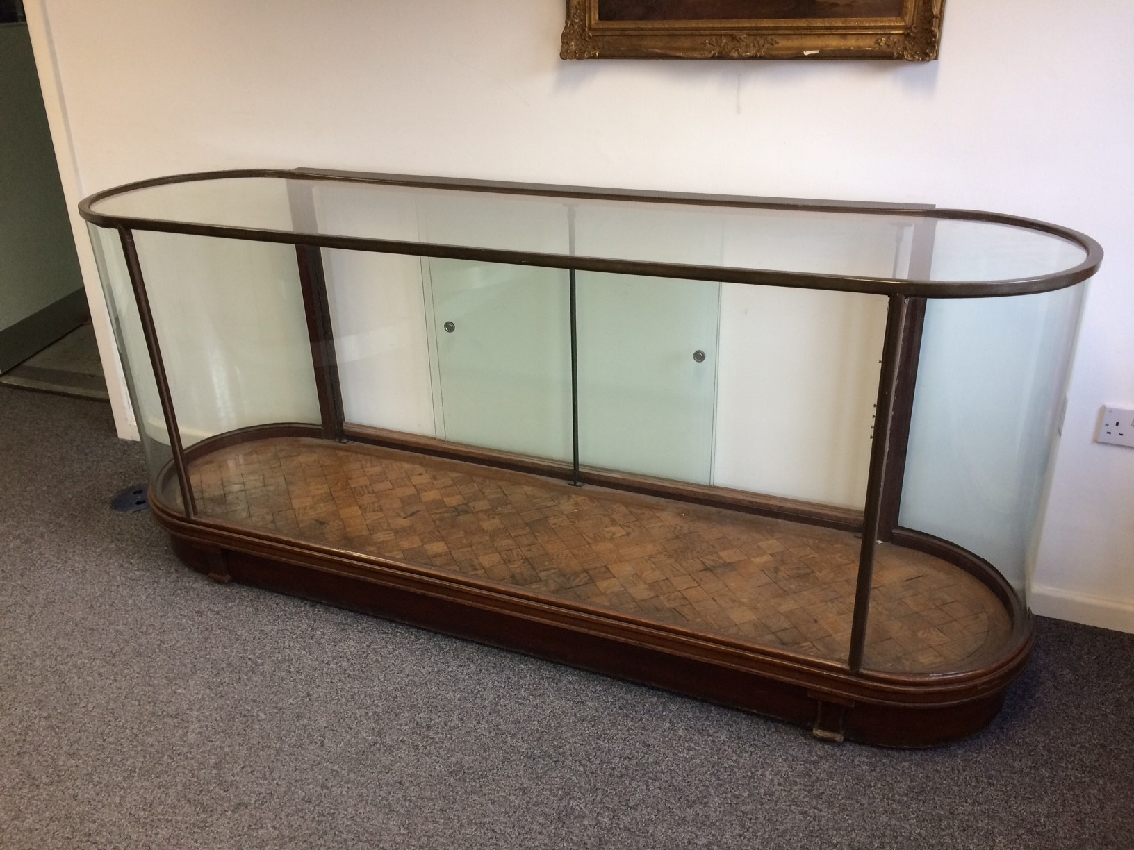 An early 20th Century brass framed and glazed shop display counter with D shaped ends,