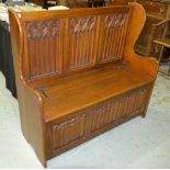 A reproduction oak linen fold settle in the 17th Century style, with hinged box seat, 112cm wide.