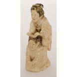 A Japanese Meiji period carved ivory okimono of a Geisha girl combing the hair of a maiko dancing