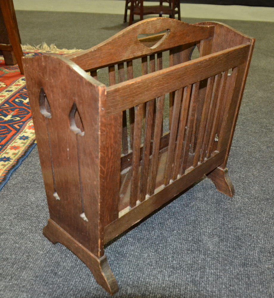 A Liberty style oak magazine rack with slatted sides and shaped ends,