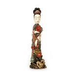 A Meiji period Japanese ivory okimono modelled as a geisha girl standing amidst rocks and lotus