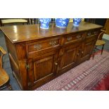 An 18th Century style oak dresser base fitted with three drawers over three fielded panelled doors