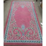 An attractive pink ground Dun Emer Rug, with plain centre and purple ground floral border,