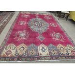A large claret ground Middle Eastern Carpet, with a large central blue ground floral design,