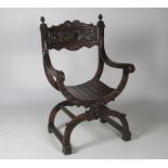 A finely carved 19th Century X shaped Armchair, decorated with grotesque mask heads, scrolls,