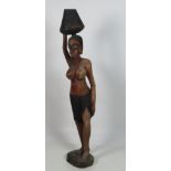 An early 20th Century tall African figure of a Native Lady carrying a vessel on her head,