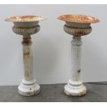 A pair of smaller attractive classical style cast iron urns, on pillar type plinths, approx.