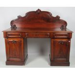 A Victorian mahogany pedestal Sideboard, with carved and scroll shaped back on a moulded top,