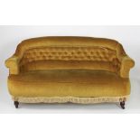 A Victorian button back three seater Couch, on front turned mahogany legs with castors,