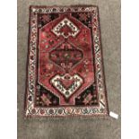 A small heavy rose ground Oriental Rug, with three medallions and corner decorations with stars,