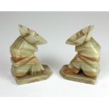 A pair of onyx marble Book Ends, modelled as a seated male and female with large hats,