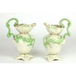 A pair of Second Period Belleek decorated Jugs, with foliage design, scroll handles,