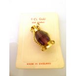 9K YELLOW GOLD JUG PENDANT WITH A PURPLE CRYSTAL IN THE CENTRE. WEIGHT IN TOTAL 5.4G