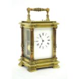 Large brass repeating carriage clock striking on a gong, within a pillared stepped breakfront case