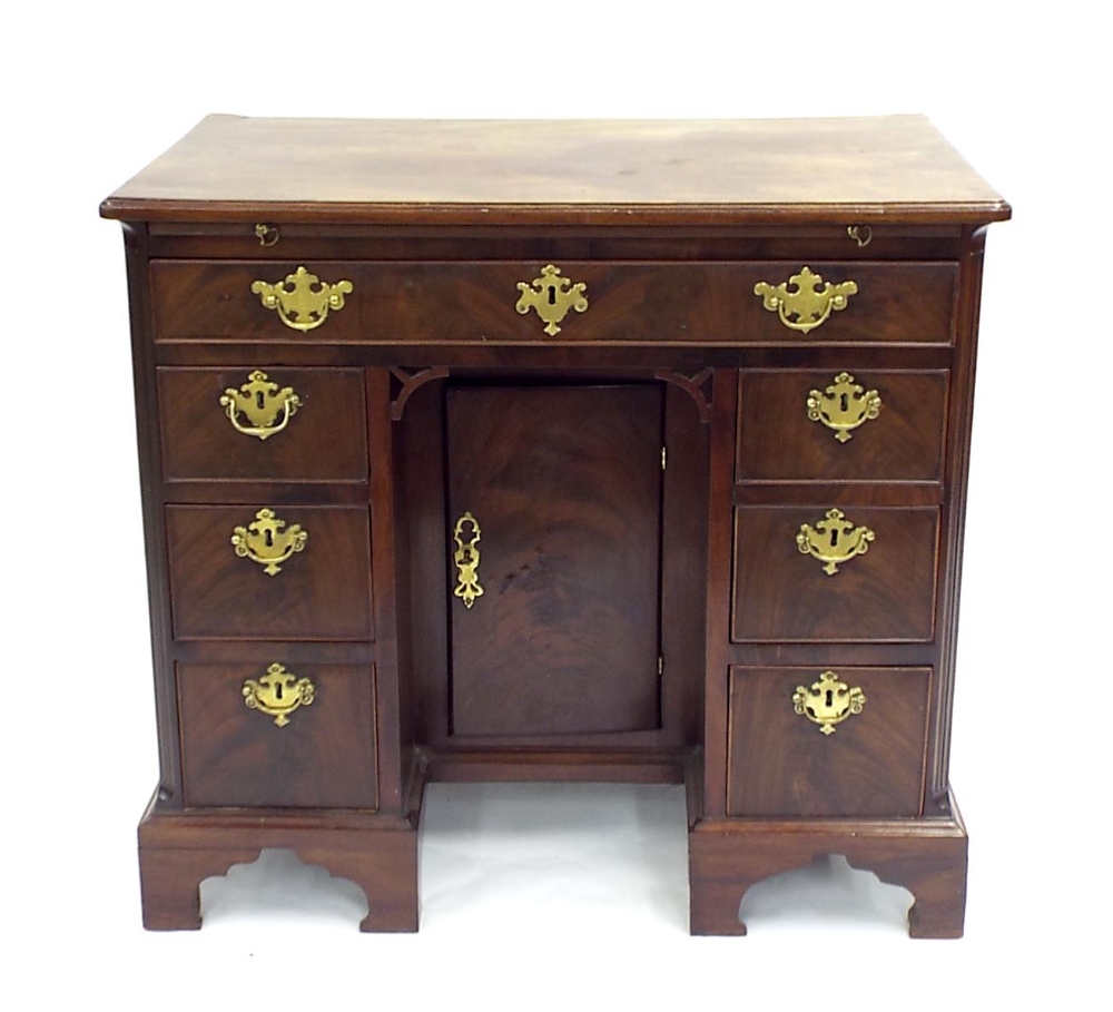 George III flame mahogany kneehole desk fitted with a brush slide over an arrangement of seven