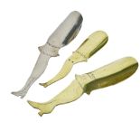 Two engraved novelty brass shoe horns in the form of a lady's leg, along with a further white