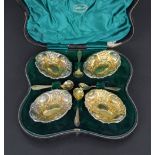 Fine cased set of four oval silver-gilt pedestal salts and matching spoons, repousse with foliate