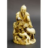 Japanese carved stained ivory okimono, modelled with two figures in a naturalistic setting holding