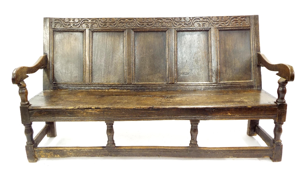 17th century oak settle, the cresting rail carved with stylised foliage and the initials I G,