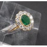 Fancy 18ct emerald and diamond oval cluster ring, the central emerald 0.84ct approx, within a