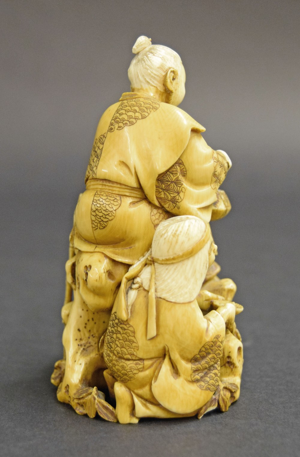 Japanese carved stained ivory okimono, modelled with two figures in a naturalistic setting holding - Image 2 of 3