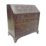 19th century carved oak bureau in the Flemish manner, the fall front carved with three bust