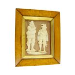 Framed pair of carved ivory figures in the Bavarian manner of gentlemen playing bagpipes and a