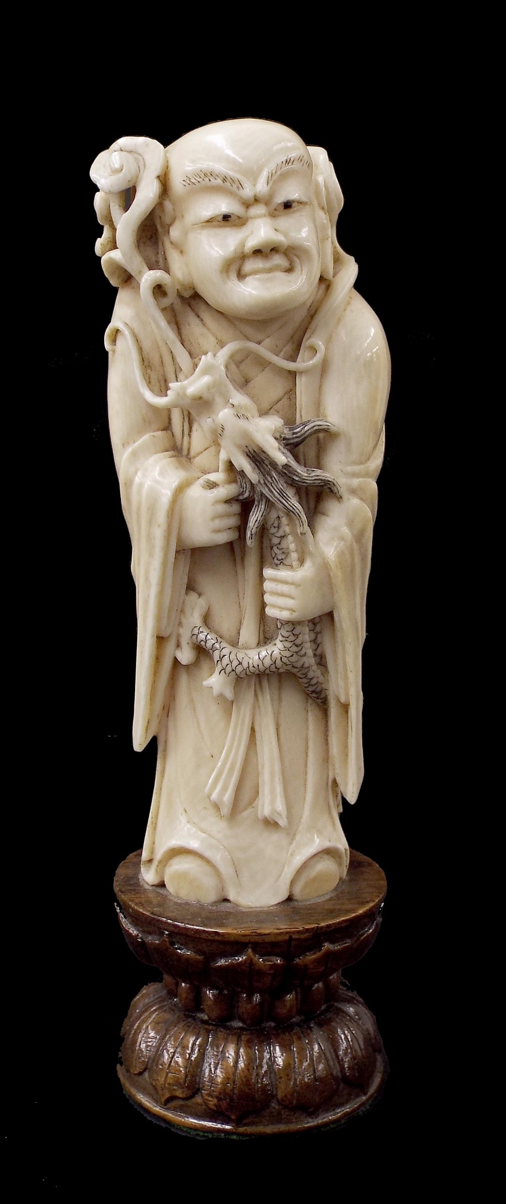 Japanese ivory okimono, finely carved and modelled as a sage holding a smoke-blowing dragon, fixed