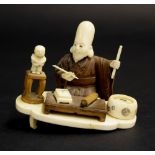 Japanese small ivory and hardwood okimono, modelled as a scholar kneeling at a low table on a
