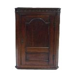 Georgian oak corner cupboard, the blind fretwork cornice over a panelled cupboard door enclosing a