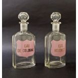 Pair of French clear glass perfume bottles with facet-cut stoppers, labelled 'Eau De Cologne' and '
